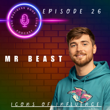 Young man with brown hair smiling, wearing a blue hoodie, in front of a brick wall.