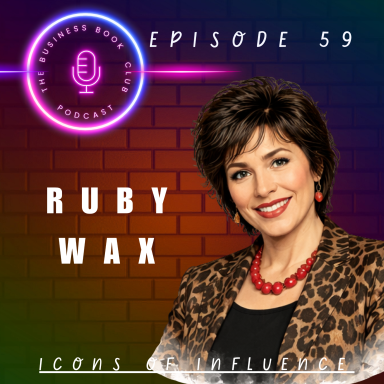 Portrait of Ruby Wax with a bold patterned top, smiling, against a colourful background.