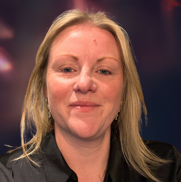 A smiling woman with long blonde hair wearing a black shirt.